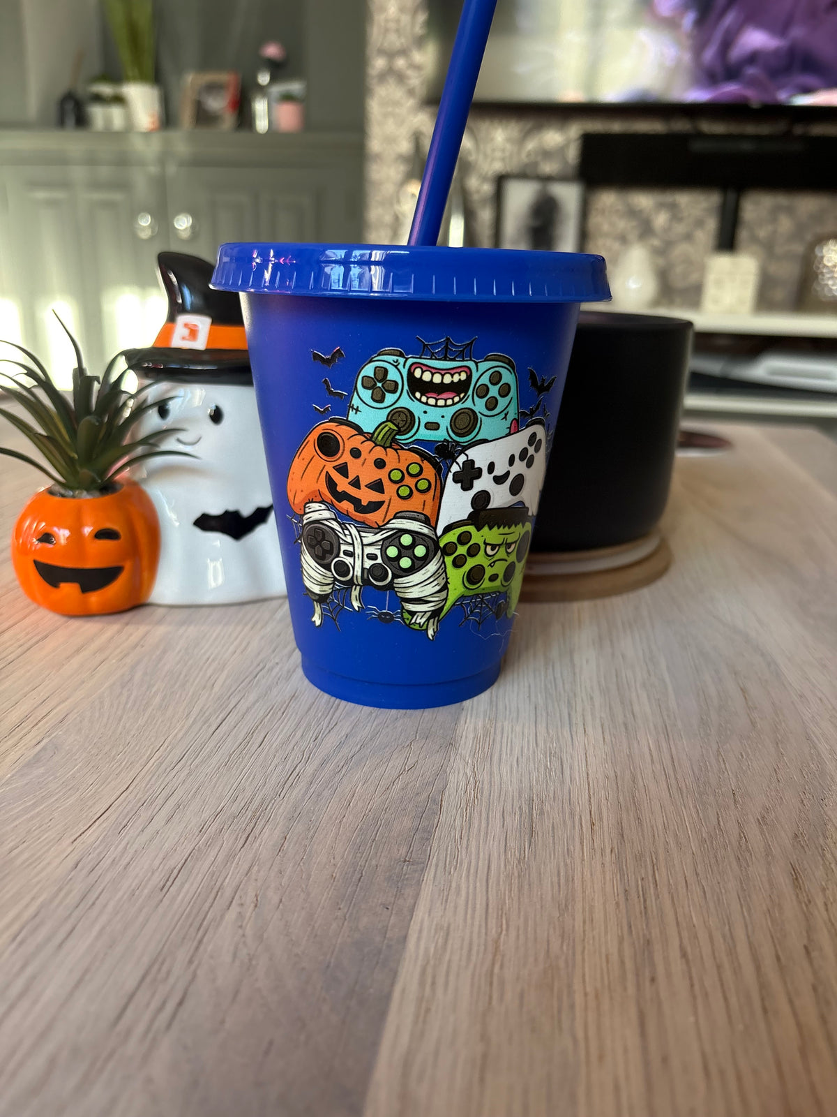 Blue 16oz kids Halloween cold cup with lid and straw, decorated with spooky gaming controllers dressed as a pumpkin, mummy and monster
