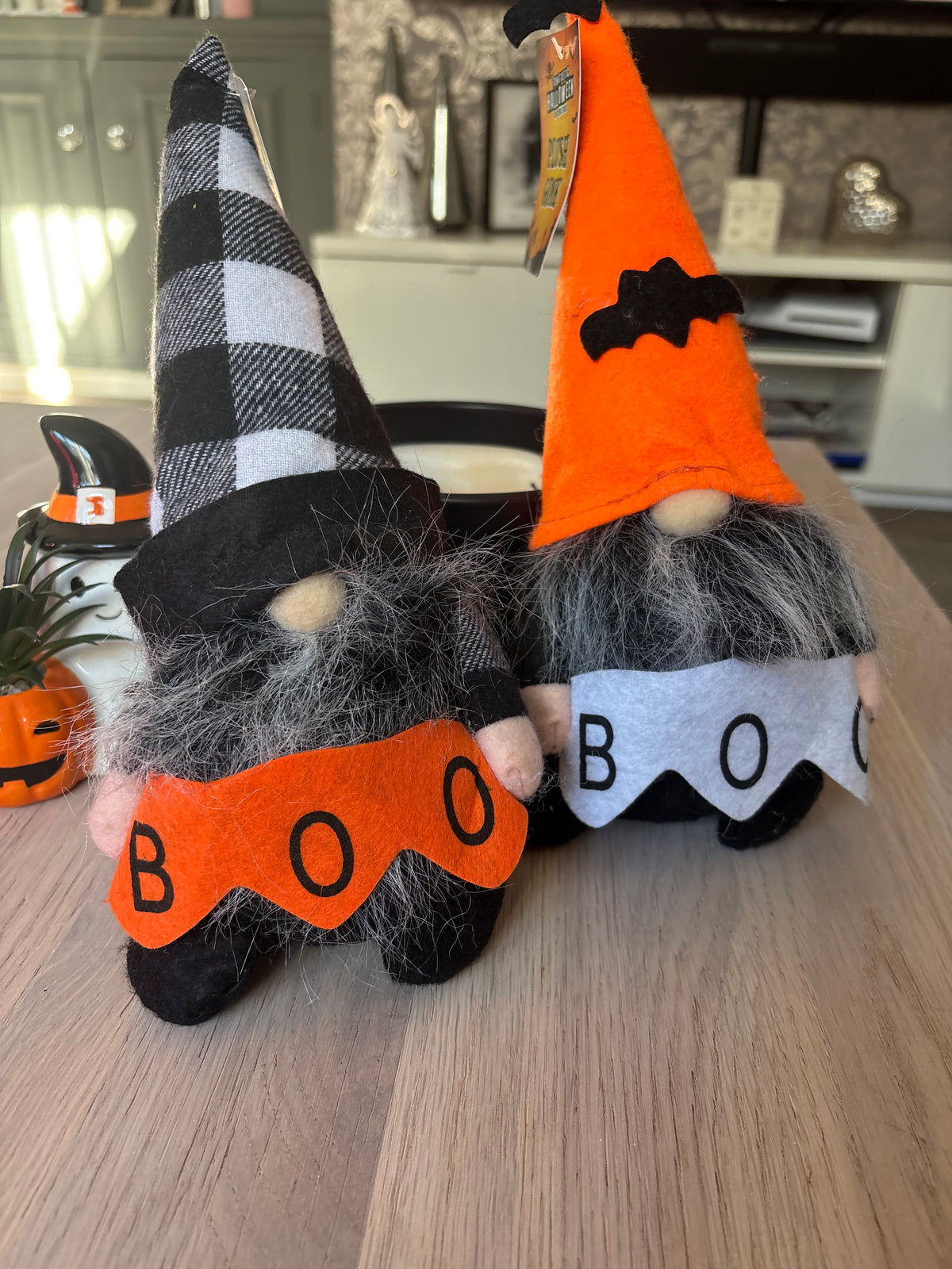 Two Halloween decor gonks, one with a black-and-white check hat and orange BOO banner, one with an orange bat hat and white BOO banner