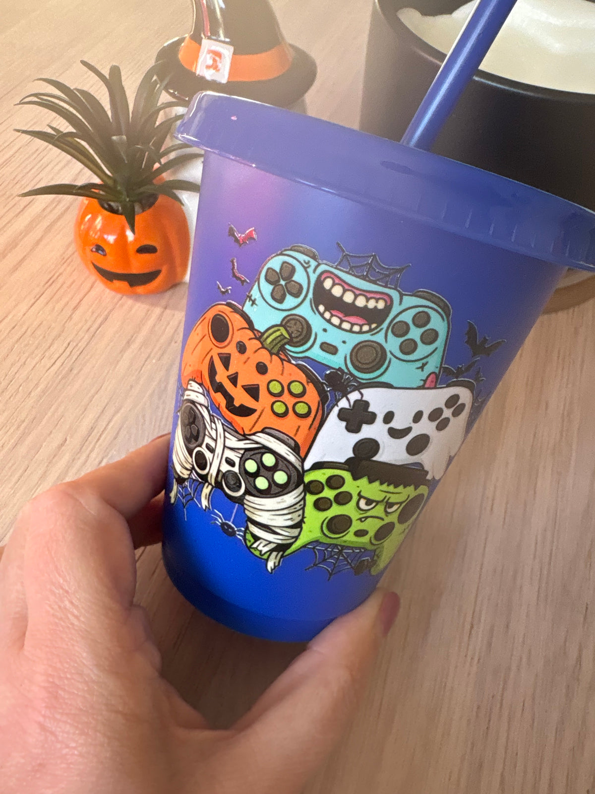 Blue kids gamer cup beside a ghost and pumpkin Halloween decorations