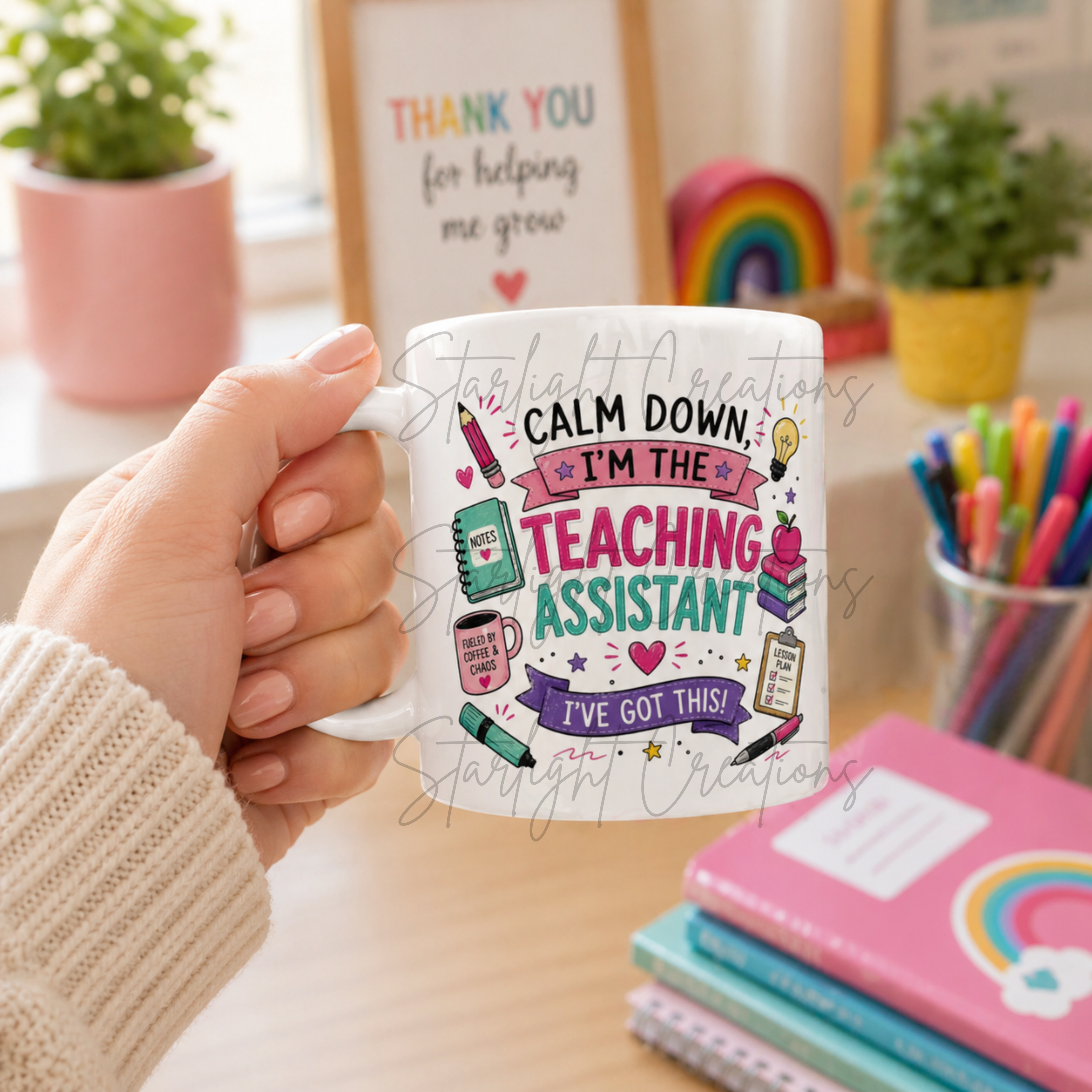 Person holding a mug with a colorful design and text, surrounded by stationery items on a desk.