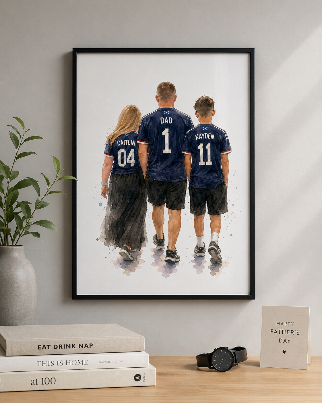 artwork of a family in matching jerseys on a wall above books and a plant.