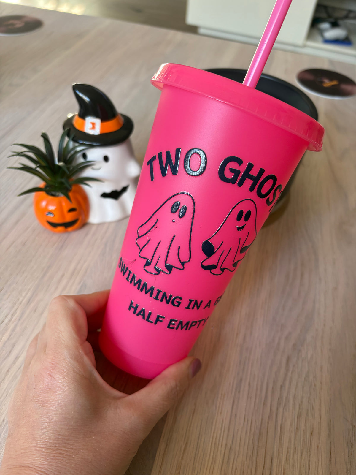 Close-up of two cartoon ghosts, one worried and one smiling, in black vinyl on a pink tumbler