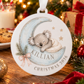 Personalised acrylic koala bauble with a baby’s name and Christmas 2026, hanging among festive lights and treats