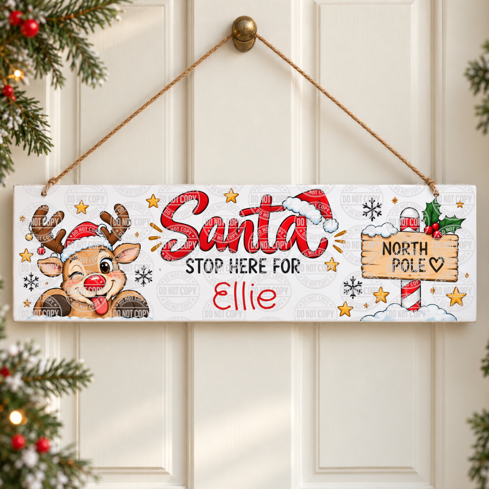 Personalised Santa stop here sign with a cheeky reindeer and North Pole signpost. Wooden hanging sign, 28cm long, with the name you choose. Order now.