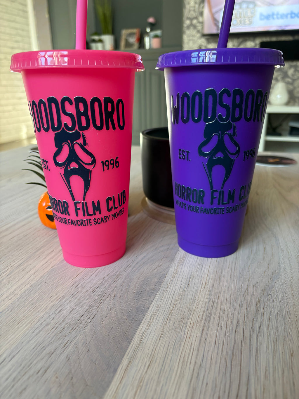 Pink and purple Woodsboro horror film club cold cups side by side