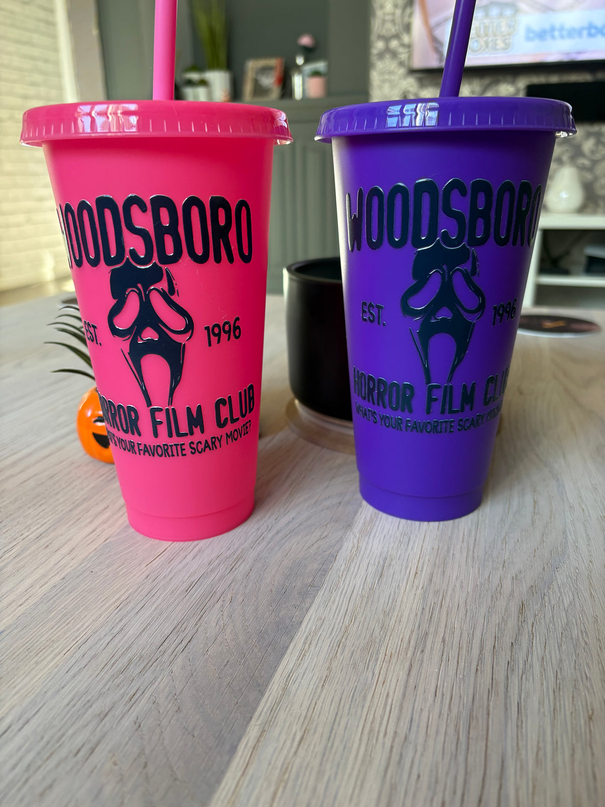 Pink and purple Woodsboro horror film club cold cups side by side