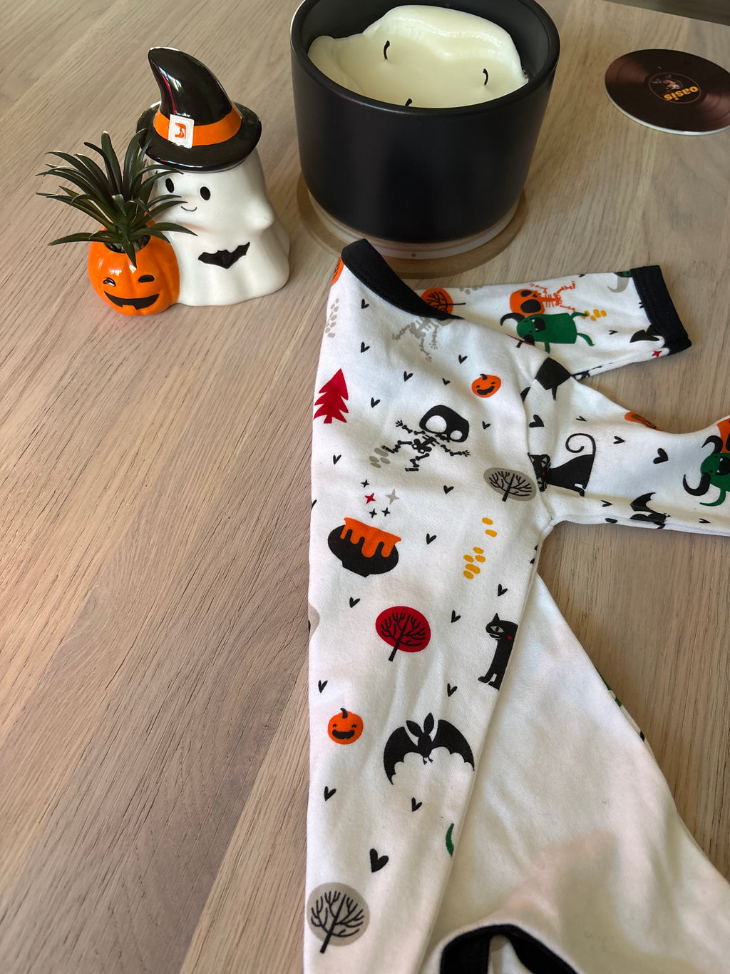 Close-up of spooky-print sleeve with black trim on a white baby Halloween sleepsuit