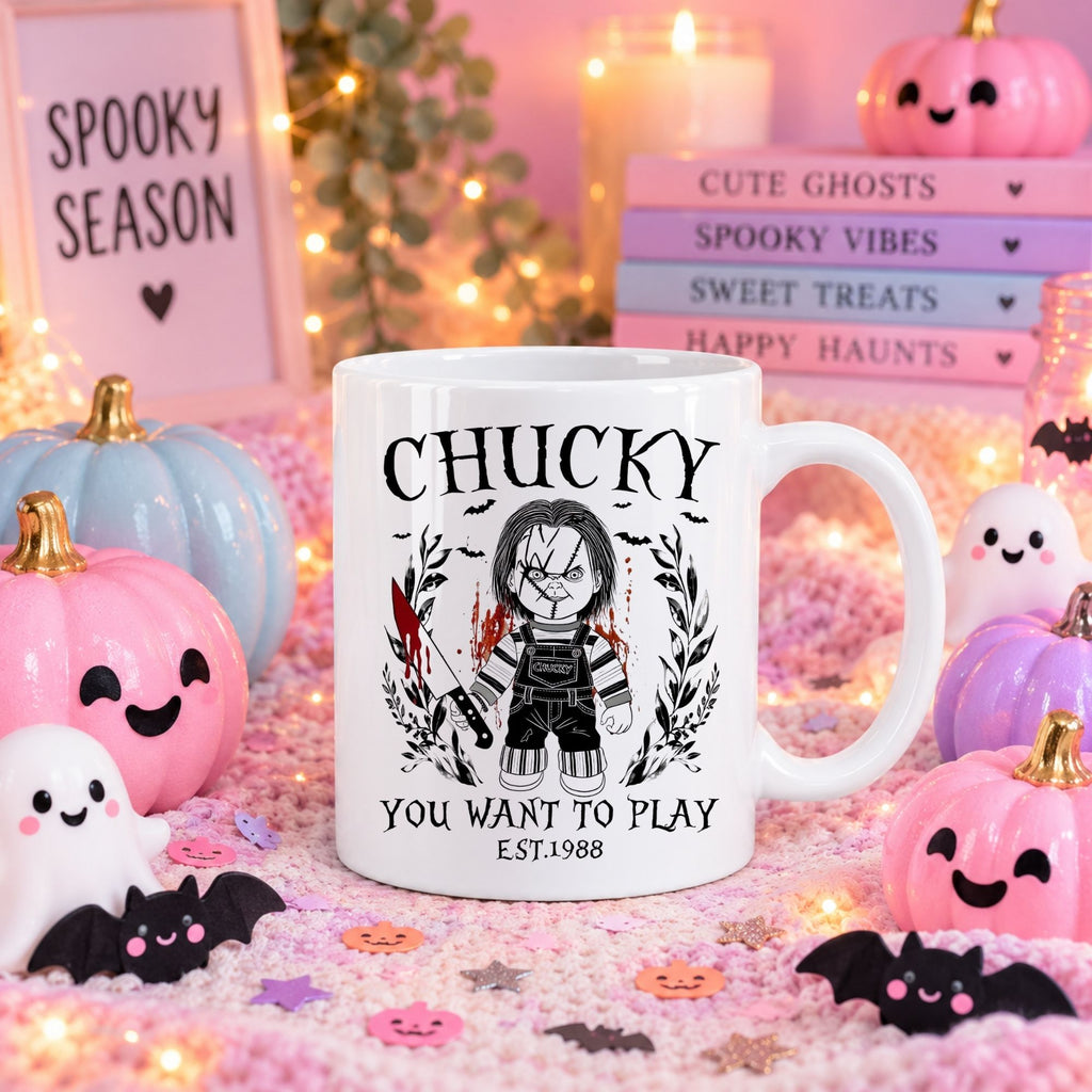 A white ceramic mug with a Chucky graphic print, set in a festive Halloween-themed scene with pumpkins, candles, and themed books.