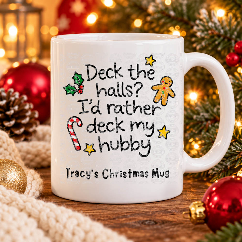 White ceramic funny Christmas mug with the slogan “Deck the halls? I’d rather deck my hubby”, gingerbread man, candy cane and holly, topped with marshmallows and cocoa