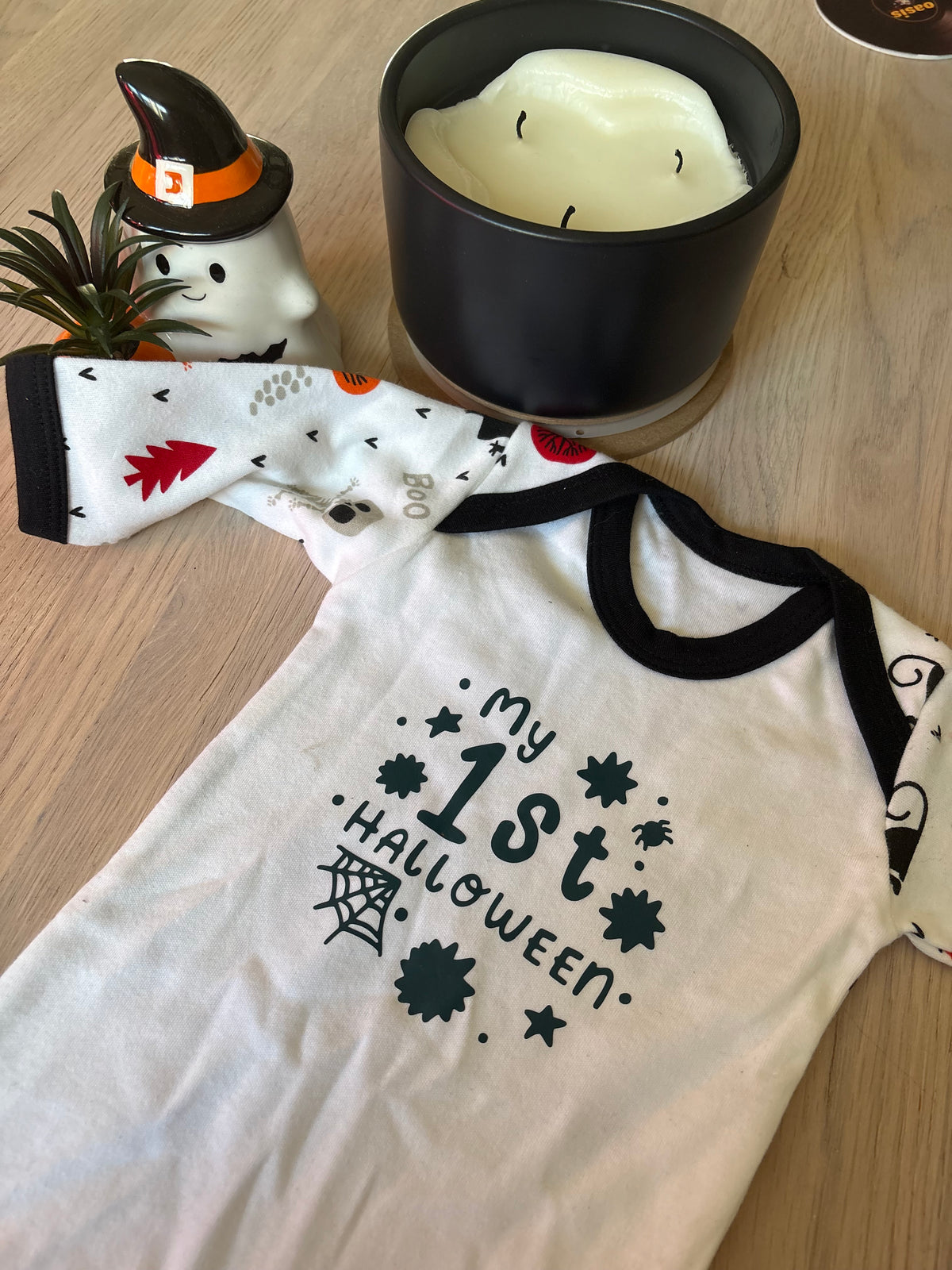 White cotton newborn babygrow with black trim and “My 1st Halloween” spiderweb and stars design on the front
