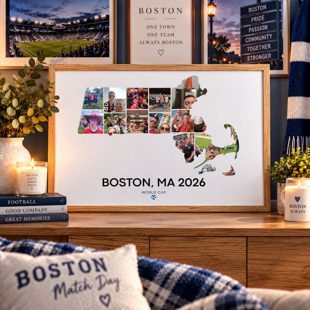 A framed personalized Boston sports print displayed on a wooden cabinet in a cozy room setting. The print features a collage of photos arranged in the shape of Massachusetts, with 'BOSTON, MA 2026' and the FIFA World Cup logo printed below.