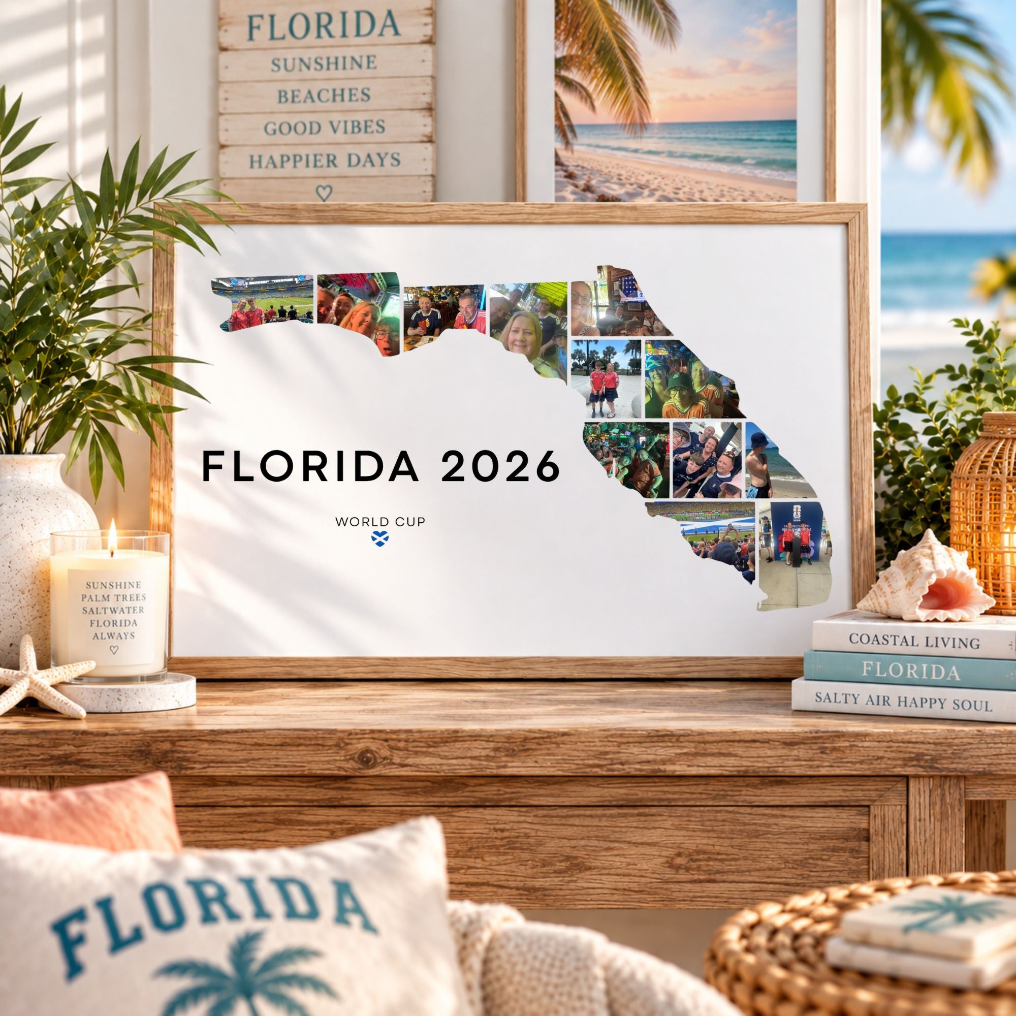 A framed Florida state silhouette print with the text 'FLORIDA 2026' and a collage of photos along the right side, displayed on a wooden console in a styled room with beach-themed decor, pillows, plants, and books.